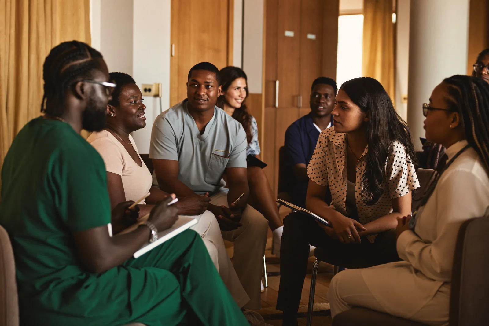 A small classroom discussion among adult healthcare students seated in a semicircle with their instructor